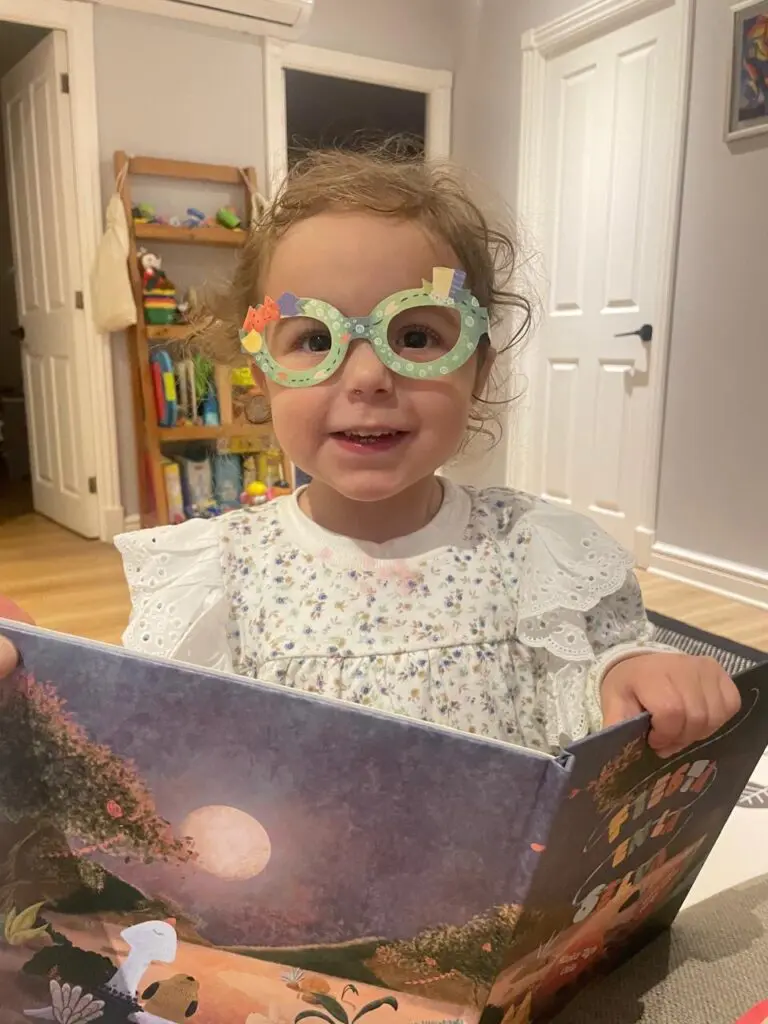 Niña con lentes lee un libro