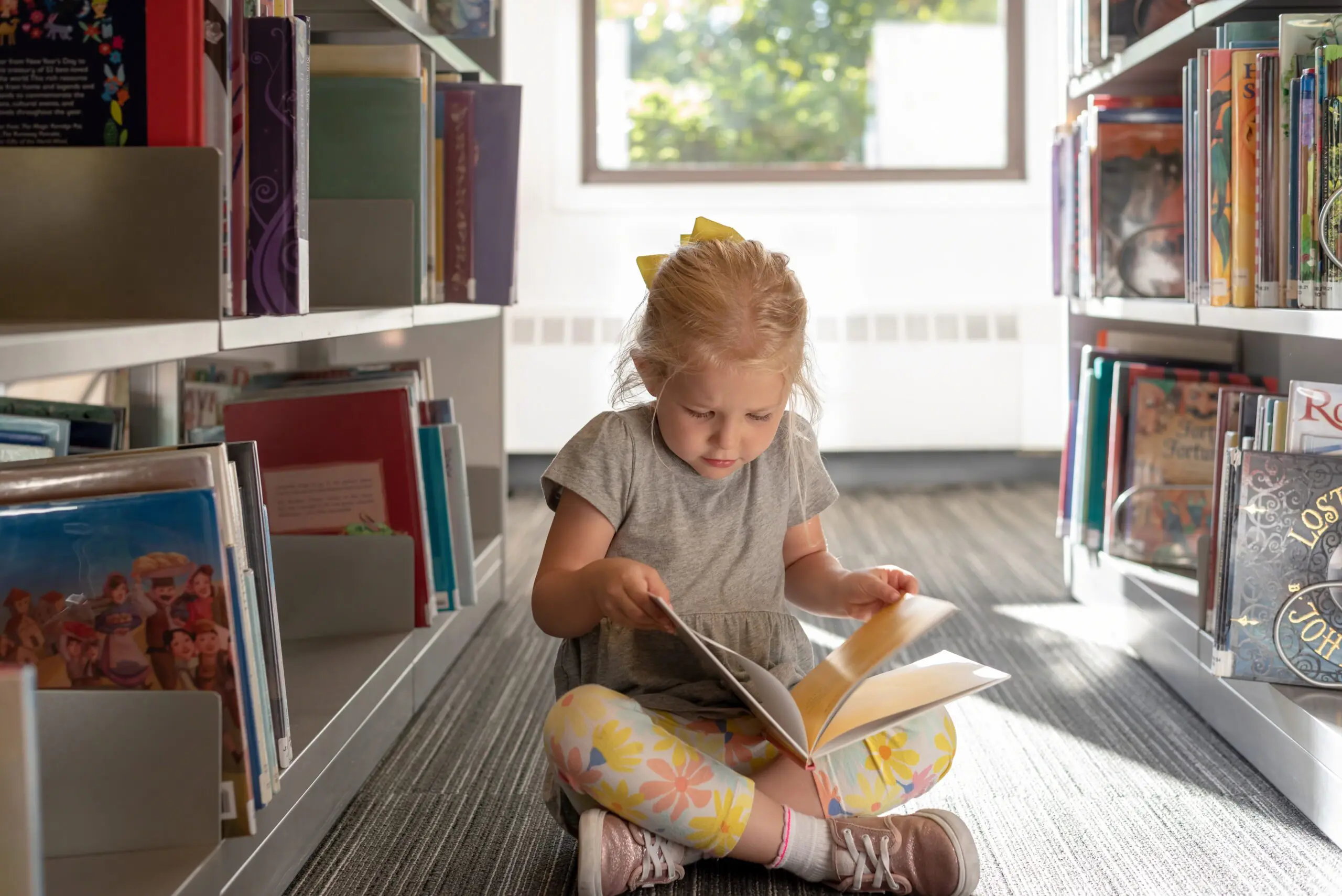 Little girl reading a book at the library