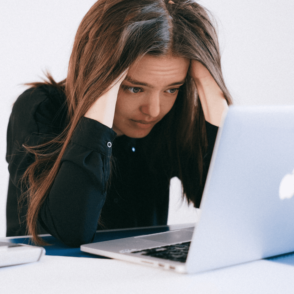 Mujer mirando la pantalla de un computador con aspecto cansada y ansiosa